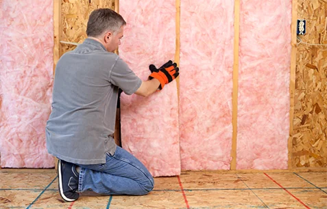 Technician installing batt insulation